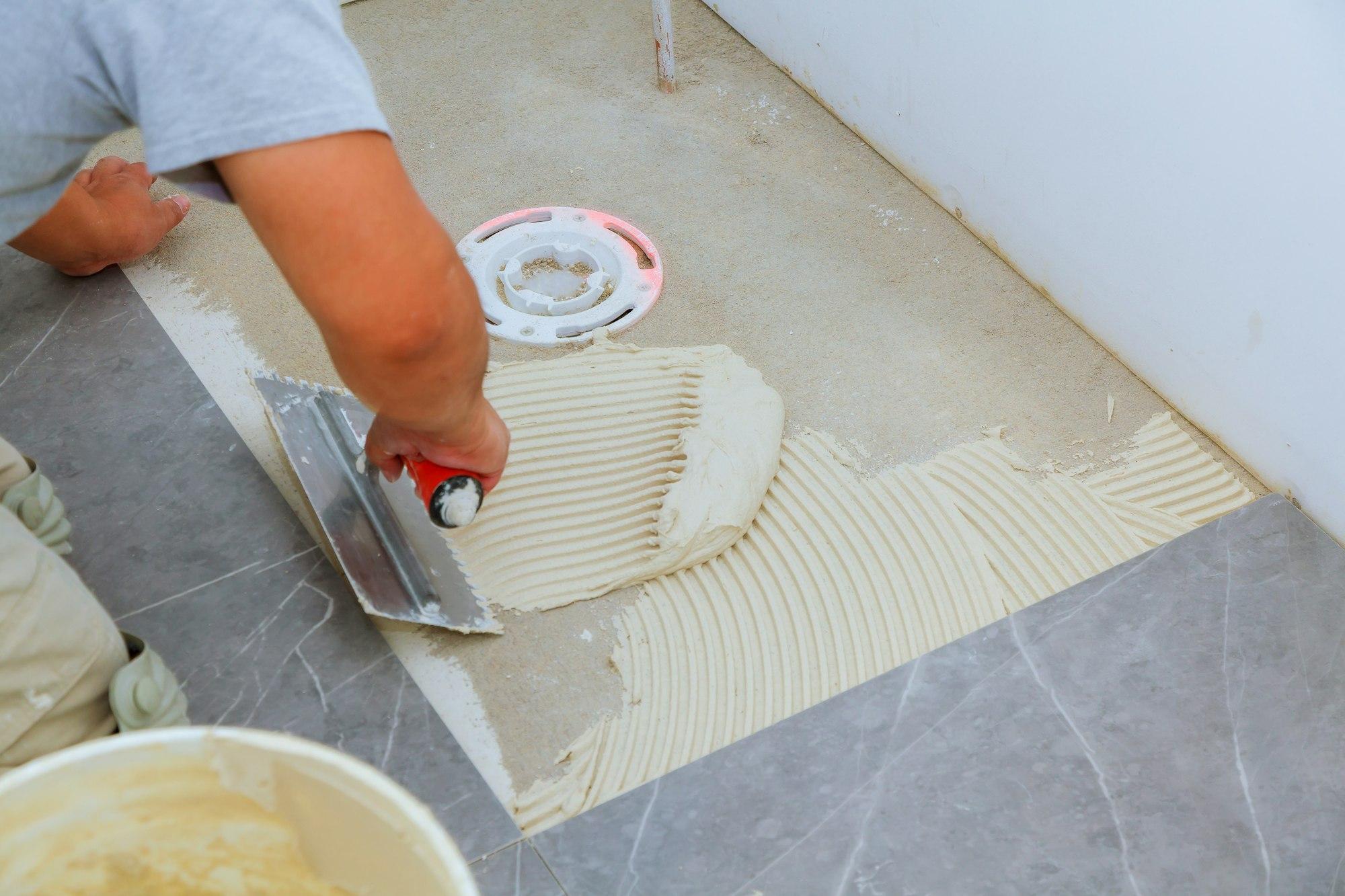 The master the tile industrial tiler builder worker installing floor tile